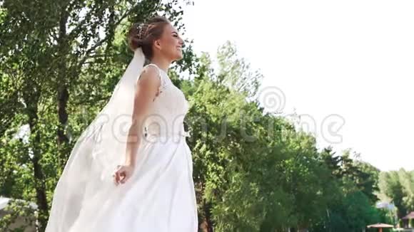 从下面看到一个穿着白色裙子的年轻快乐新娘视频的预览图