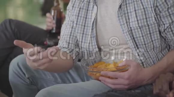 朋友们可以休息一下喝啤酒吃薯片坐在室内沙发上视频的预览图