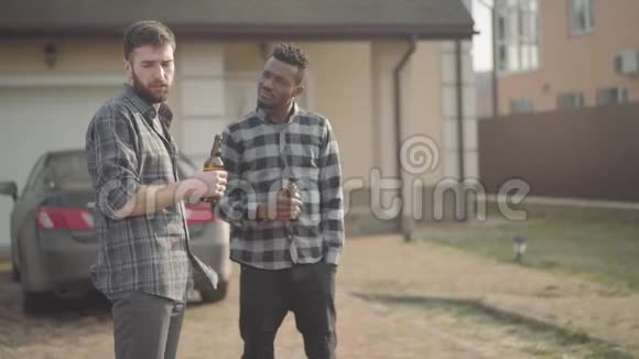 两个白人和非裔美国人站在大房子前喝啤酒第三个朋友来了视频的预览图