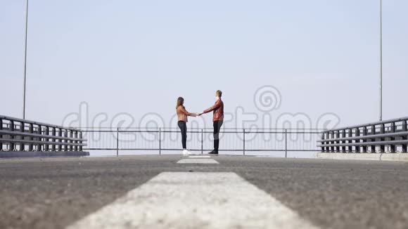 在远处两个可爱的年轻人和你的女人站在路上牵手视频的预览图