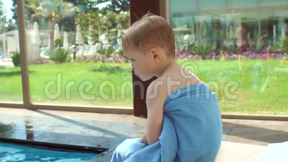 小金发男孩在游泳池游泳后裹着毛巾视频的预览图