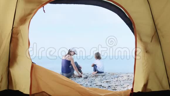 妈妈正和她的小女儿在海边用石头建造一座塔视频的预览图