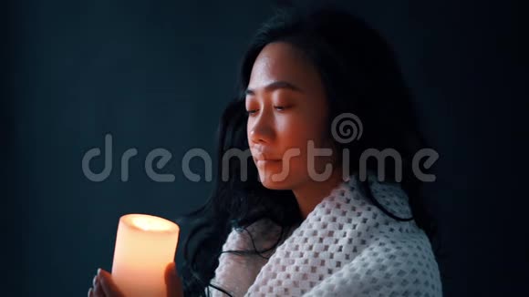 美丽的亚洲女人在黑暗的背景下吹蜡烛视频的预览图