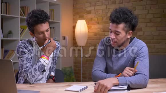 非裔美国和印度男学生一起学习的特写镜头两个朋友在玩抽搐战术视频的预览图