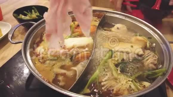 在涮锅涮锅涮锅或烧锅中啜饮猪肉片和蔬菜片视频的预览图