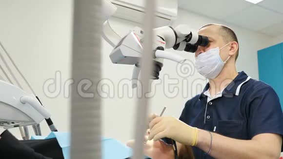 带有显微镜目镜的牙医牙医在现代牙科诊所治疗病人带牙具的男性牙医视频的预览图
