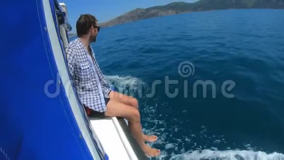 英俊的年轻人坐在船上或游艇上漂浮在海里暑假和朋友一起慢动作视频的预览图