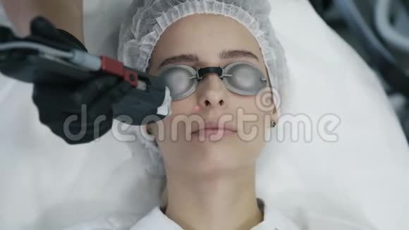 特写美容师用专用设备对女性面部进行激光血管切除术视频的预览图