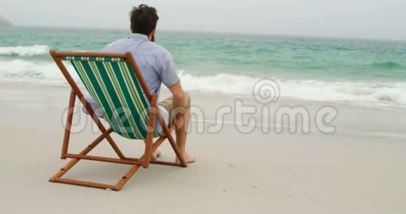 人的后视图放松双手背在沙滩上的阳光休息室视频的预览图