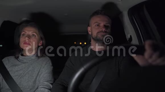 一对夫妇在晚上骑着一辆车当警察的灯光在背景上闪烁时他们开始互相尖叫视频的预览图