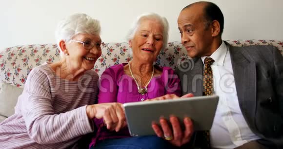 一群活跃的混血高级朋友在养老院讨论数字平板电脑视频的预览图