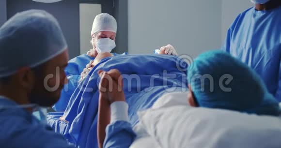 高加索女外科医生在医院手术室分娩时检查孕妇视频的预览图