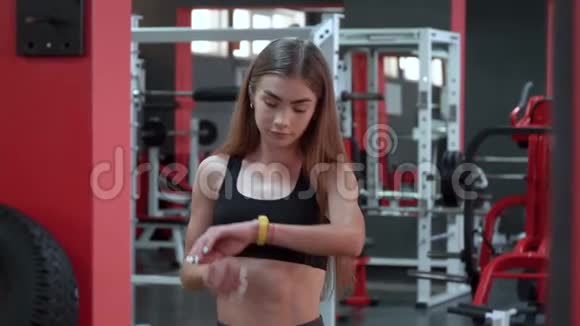黄色智能手表显示年轻女子在健身房锻炼的心率视频的预览图