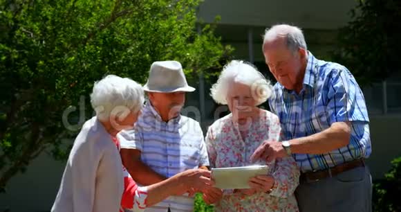 白种人老年夫妇在养老院花园讨论数字平板电脑视频的预览图