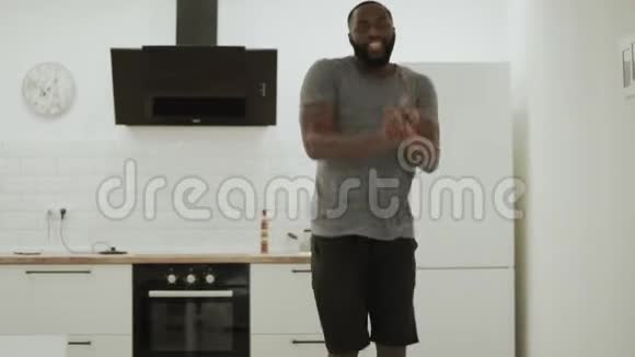 欢乐的黑人男子在开放式厨房拍手快乐的年轻人在家跳舞视频的预览图