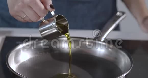 厨师把橄榄油从金属碗中倒入热锅中做一道油炸菜视频的预览图