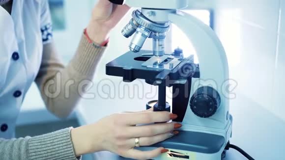 穿着白色外套的专业女性实验室助理在显微镜后面工作视频的预览图