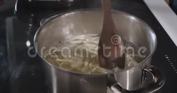 将意大利面条与木制勺子混合在钢盘上慢动作视频的预览图