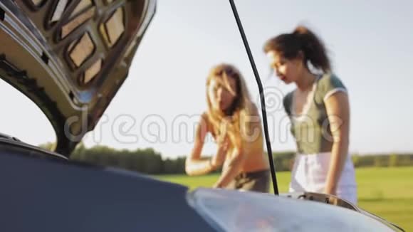 两个穿短裤的性感女孩和一件t恤站在树林里的路上的敞篷汽车前决定视频的预览图