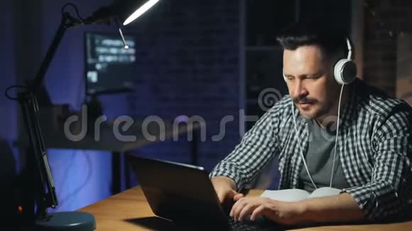 快乐的男人在黑暗的办公室里忙着手提电脑跳舞视频的预览图