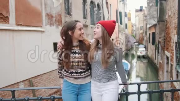 意大利威尼斯两个年轻女子站在水道上方的小桥上兴奋地环顾四周视频的预览图