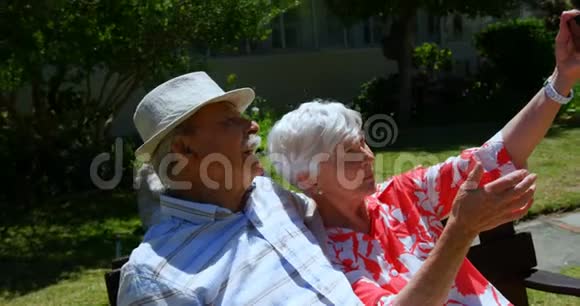 积极的高加索老夫妇在保姆园用手机自拍的正面景色视频的预览图