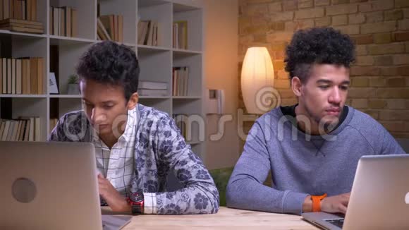 印度和非裔美国男学生使用笔记本电脑和在线学习的特写镜头一个问另一个视频的预览图