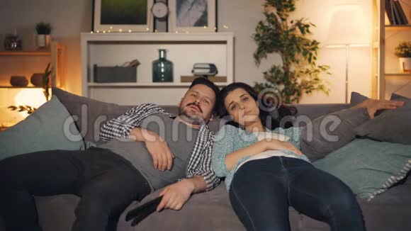 疲倦和困倦的人男人和女人在家里沙发上打哈欠看电视视频的预览图