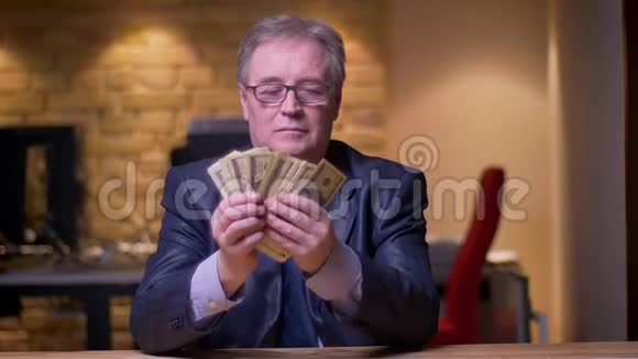 一幅高级商人穿着正式服装数着钱在办公室高兴的肖像视频的预览图