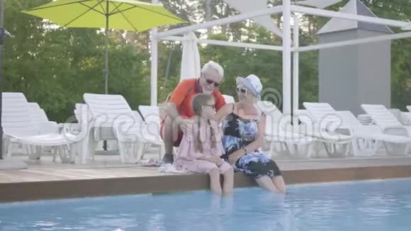 欢乐快乐的奶奶爷爷和小孙女在豪华泳池边休息视频的预览图