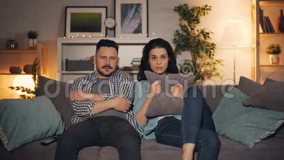 丈夫和妻子在电视上看恐怖电影看着镜头脸上带着恐惧视频的预览图