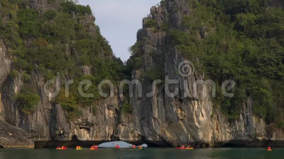 游客乘坐皮艇或独木舟探索越南海龙湾的洞穴和石灰岩岛屿视频的预览图