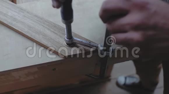 特写一个木匠安装一个木制部分在一个角度使用一个正方形保持部分与一个夹子4k4k录像60英尺视频的预览图