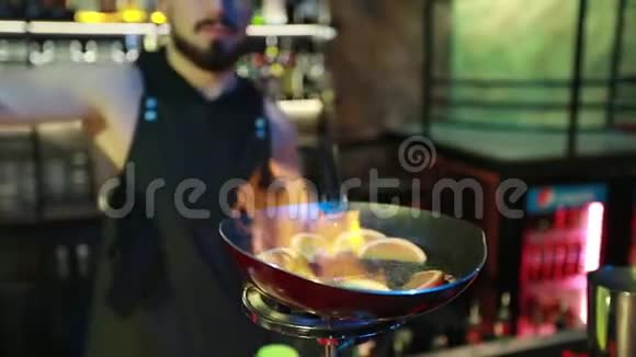 大胡子的酒保把肉桂倒入一个锅里在煤气炉上放橘子视频的预览图