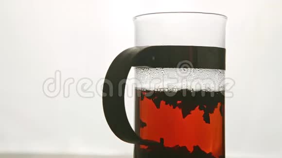 带有红茶的特写玻璃茶壶在基座上与白色旋转视频的预览图