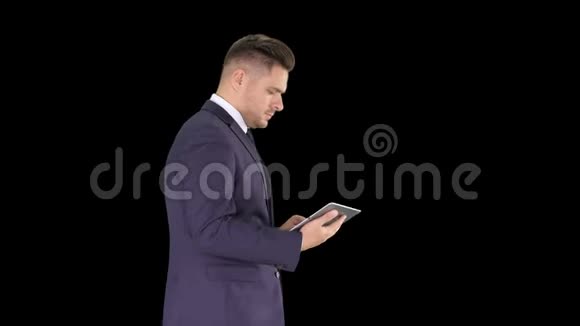优雅的年轻商人在走路时使用他的电脑平板电脑阿尔法频道视频的预览图