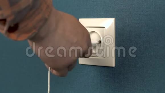 一个男人把电话充电器插入墙上的插座墙上的罗塞特和深蓝色壁纸特写视频的预览图