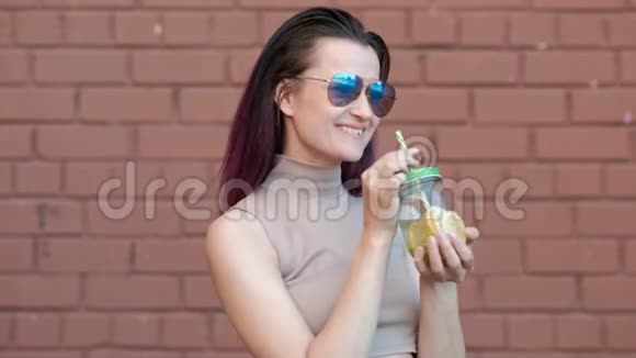 戴着墨镜的年轻美女正在喝着杯中的柠檬水鸡尾酒背景是一根吸管视频的预览图