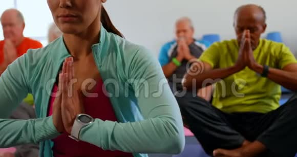 积极的混合种族高级人士和教练在健身工作室4k表演瑜伽的正面视图视频的预览图
