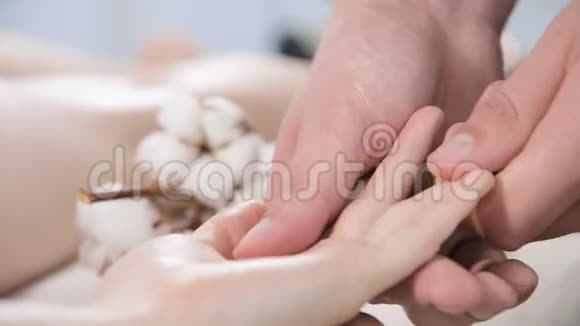 一名男性理疗师在按摩水疗沙龙为一名年轻女孩做手指和手掌按摩专业人员视频的预览图