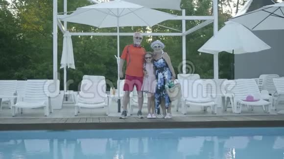 幸福成熟的夫妇站在游泳池拥抱他们的小孙女祖母和祖父视频的预览图