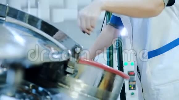 穿着白色外套的女人打开啤酒酿造罐的舱口视频的预览图