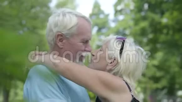 成熟的夫妻接吻微笑着看着镜头年长的女人拥抱她的丈夫可爱的幸福家庭视频的预览图