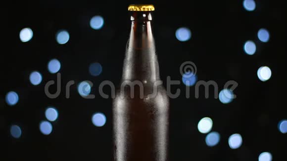 在明亮的灯光下在黑色背景上旋转的透明瓶子中的深色啤酒视频的预览图