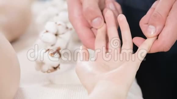 一名男性理疗师在按摩水疗沙龙为一名年轻女孩做手指和手掌按摩专业人员视频的预览图