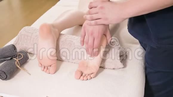 一位男性理疗师在美容和健康水疗中心为一位年轻女性做足跟足底按摩脚视频的预览图