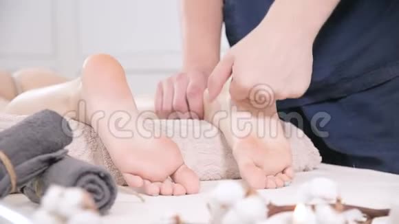 一位男性理疗师在美容和健康水疗中心为一位年轻女性做足跟足底按摩脚视频的预览图