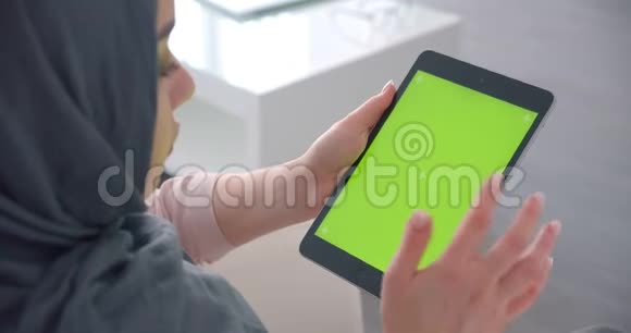 穆斯林女商人戴着头巾打开平板电脑上的应用程序屏幕上有绿色的色度并用心观看视频的预览图