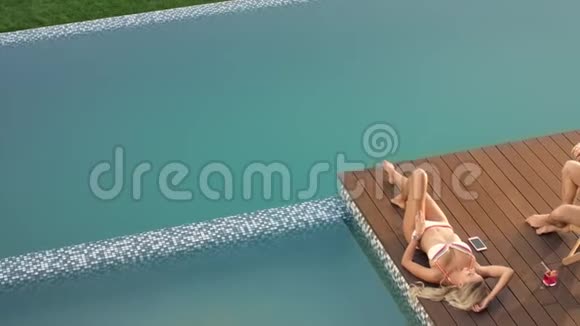 漂亮的模特和男朋友一起在泳池边晒日光浴强壮的男人拍照视频的预览图