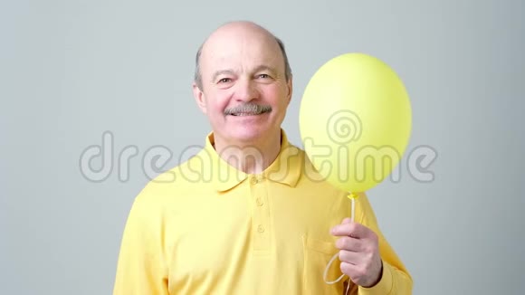 手持氦气的黄气球老人视频的预览图